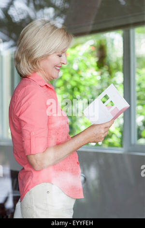 Smiling Caucasian woman reading card Stock Photo