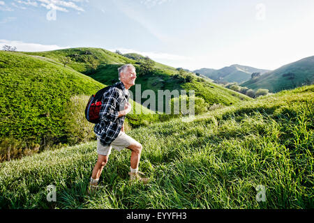 Older Caucasian man walking on grassy hillside Stock Photo