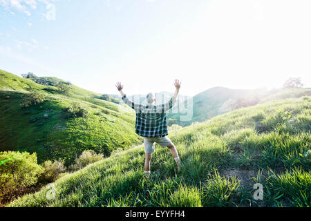 Older Caucasian man cheering on rural hillside Stock Photo