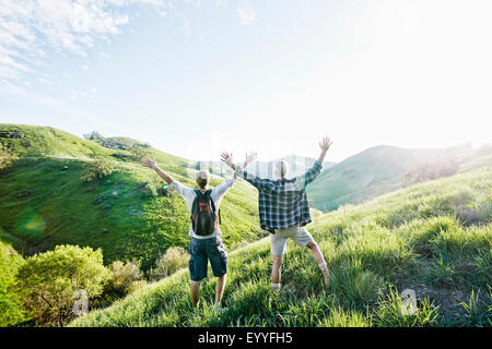 Caucasian father and son cheering on grassy hillside Stock Photo