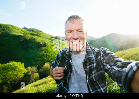 Older Caucasian man taking selfie on rural hilltop Stock Photo