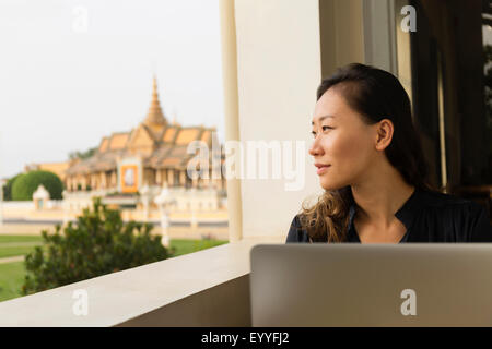 Asian businesswoman admiring view from cafe window, Phnom Penh, Cambodia Stock Photo