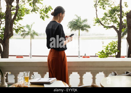 Asian businesswoman using cell phone on balcony Stock Photo