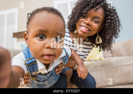 Close up of Black mother holding baby son on sofa Stock Photo