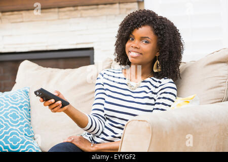 Black woman watching television on sofa Stock Photo