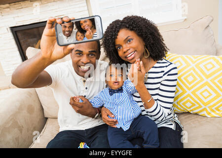 Black family taking selfie on sofa in living room Stock Photo