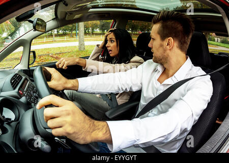 young man driving car with gesticulating young woman as co-driver, Austria Stock Photo