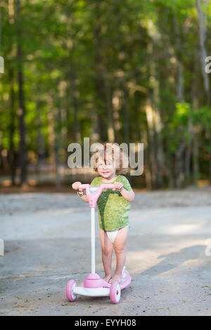Caucasian baby boy riding scooter on dirt path Stock Photo