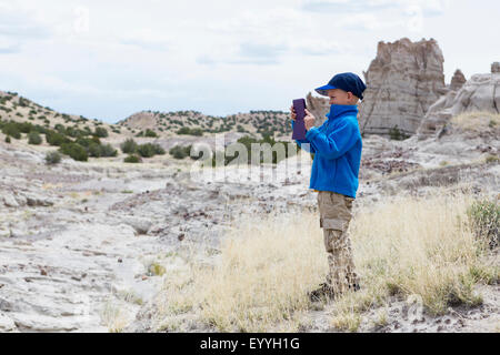 Boy photographing rock formations in desert landscape Stock Photo