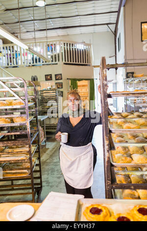 Black baker drinking coffee in bakery kitchen Stock Photo