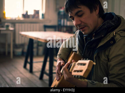 Asian man playing guitar in living room