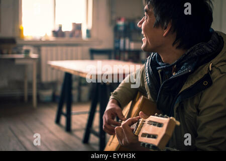 Asian man playing guitar indoors Stock Photo