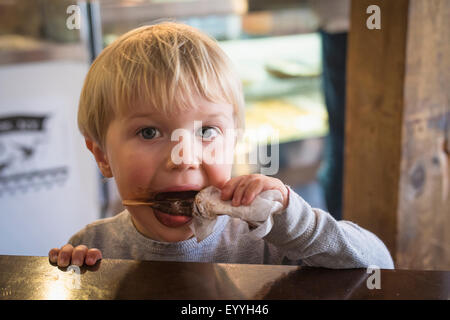 Messy Caucasian boy eating popsicle in kitchen Stock Photo