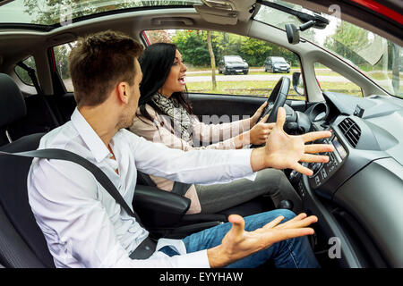young woman driving car with gesticulating man as co-driver, Austria Stock Photo