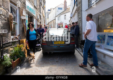 Car driving down narrow street past pedestrians in St Ives, Cornwall, England, UK Stock Photo