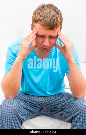 Portrait of pensive depressed man sitting on the bed Stock Photo