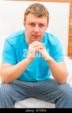 portrait of a serious man of 30 years sitting on a bed Stock Photo