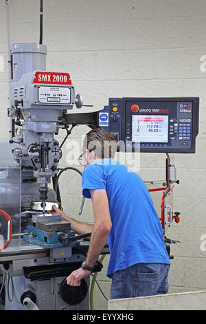 A young male worker creates a steel component using a modern, computerised drilling machine Stock Photo