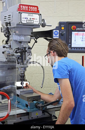 A young male worker creates a steel component using a modern, computerised drilling machine Stock Photo
