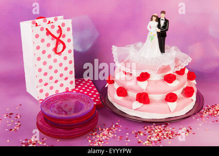 Pink wedding cake with red roses and couple on top Stock Photo