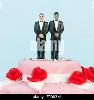 Pink wedding cake with red roses and gay couple on top Stock Photo