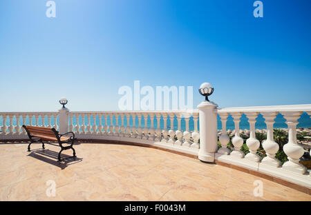 Summer view with classic white balustrade, bench and empty terrace overlooking the sea Stock Photo