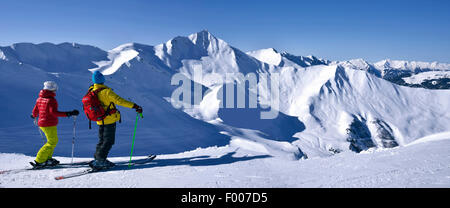 two skiers enjoying the view to snow-covered mountain scenery, France, Savoie, La Plagne Stock Photo