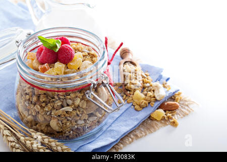 Homemade granola in a glass jar with fruit and oats Stock Photo