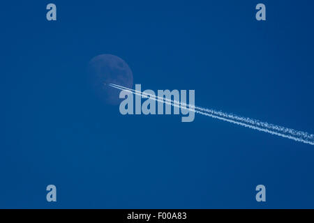 airplane with condensation trail in front of half moon, Germany, Bavaria Stock Photo