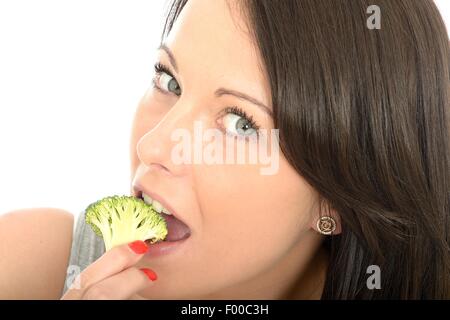 Positive Happy Young Woman Eating Healthy Uncooked Raw Broccoli Vegetables Isolated Against A White Background With A Clipping Path