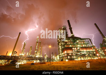 thunderstorm and lightning crashes above lightened petrochemical industry in Antwerp harbour at night, Belgium, Antwerp Stock Photo