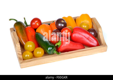 different kinds of chillies, paprikas and tomatoes on a wooden tray Stock Photo