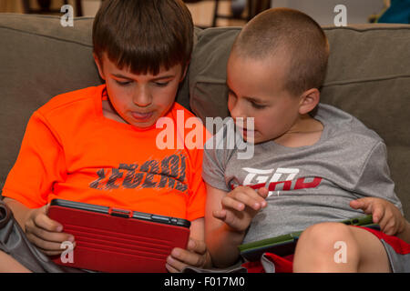 Two Brothers Playing Games on Their iPads.  MR Stock Photo