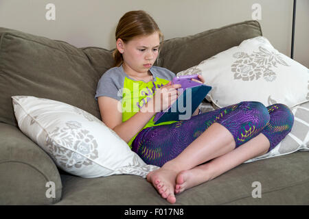 Young Girl (Eleven Years Old) Reading on her iPad.  MR Stock Photo