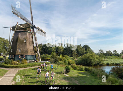 Amsterdam, the Rieker Windmill, de Riekermolen, on the Amstel River where Rembrandt used to sketch. Young tour group on bicycle. Stock Photo