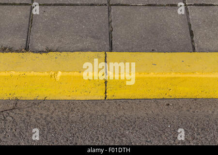Yellow curb stone border and asphalt road Stock Photo