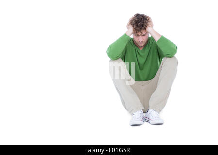 Sad casual man sitting with hand on head Stock Photo