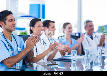 Doctors applauding while sitting at a table Stock Photo