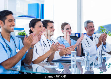 Doctors applauding while sitting at a table Stock Photo