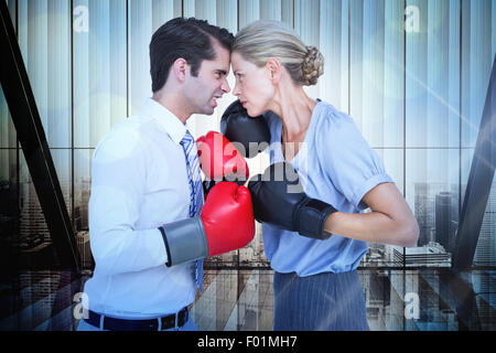 Composite image of business people wearing and boxing red gloves Stock Photo