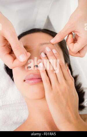 Hands threading beautiful womans eyebrow Stock Photo