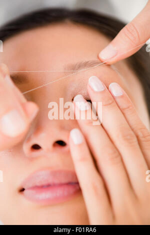 Hands threading beautiful womans eyebrow Stock Photo