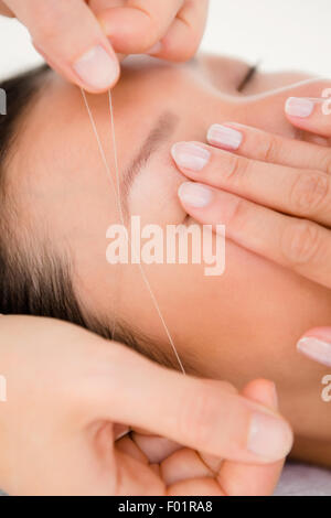 Hands threading beautiful womans eyebrow Stock Photo