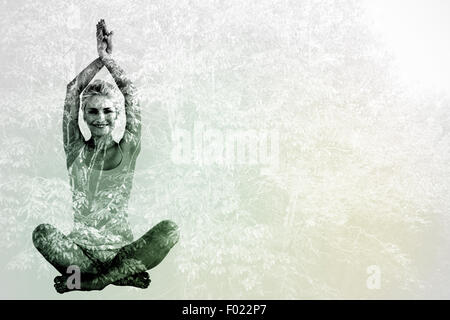 Composite image of sporty woman sitting in namaskar pose with twisted hands Stock Photo