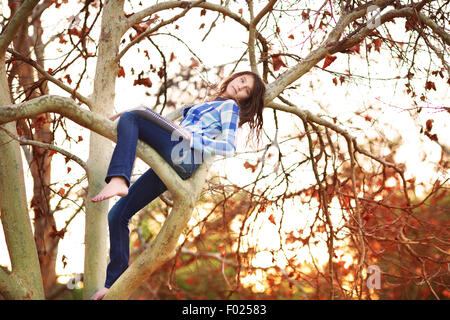 Teenage girl sitting in a tree with drawing pad, California, USA Stock Photo