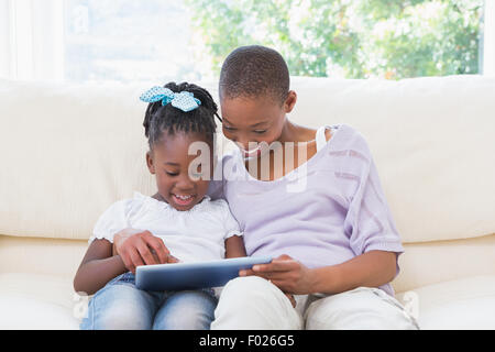Happy smiling mother using tablet with her daughter on couch Stock Photo