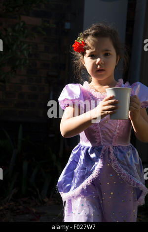 Five year old in a fancy dress bringing a cup of tea Stock Photo