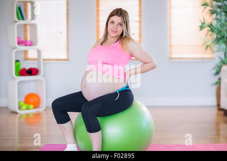Pregnant woman looking at camera sitting on exercise ball Stock Photo