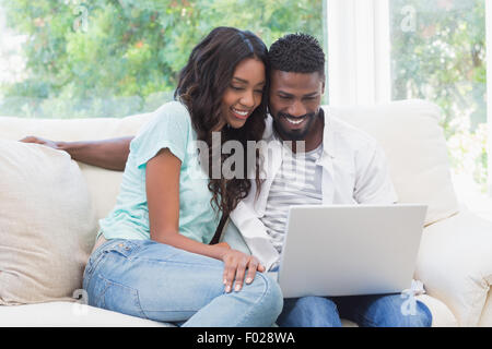 Happy couple on the couch using laptop Stock Photo