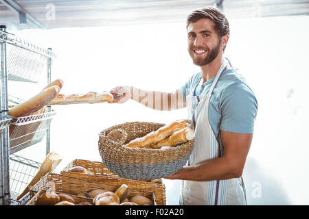 Portrait of happy worker holding basket of bread Stock Photo